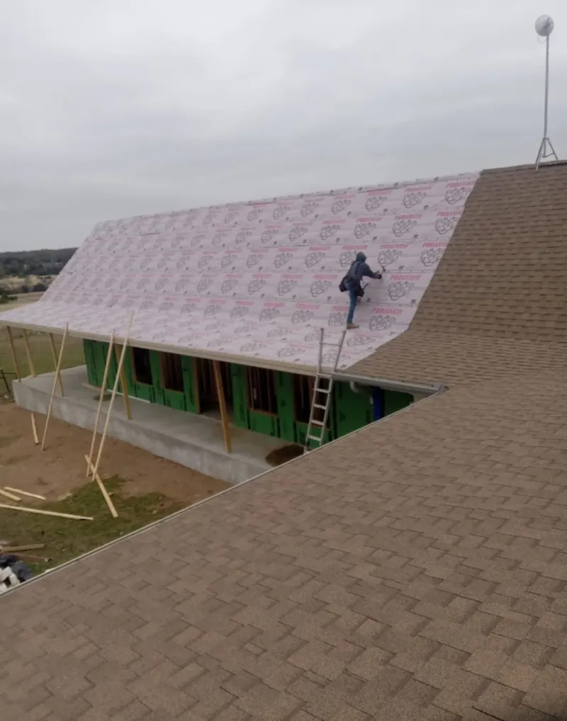 Worker preparing underlayment for a metal roof installation in Lake Shore
